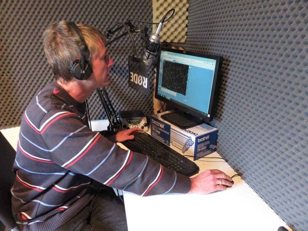 Der Meteorologe mit Kopfhörer vor einem Bildschirm